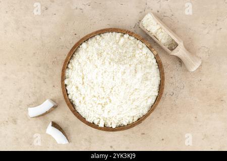Farine de noix de coco dans un bol en bois sur fond beige. Vue de dessus. Ingrédients de cuisson. Nourriture sans gluten. Banque D'Images