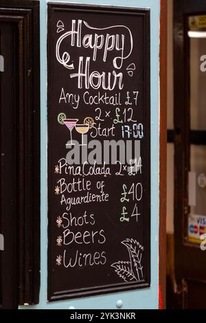 LONDRES, Royaume-Uni - 06 NOVEMBRE 2024 : craie sur panneau noir pour l'happy hour devant un bar à Brixton Banque D'Images