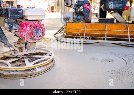 Deux types de truelle électrique auto-nivelante avec moteur à gaz ont des roues avec patins, plaque et il la conduit en cercles lissage de surface sur conc Banque D'Images