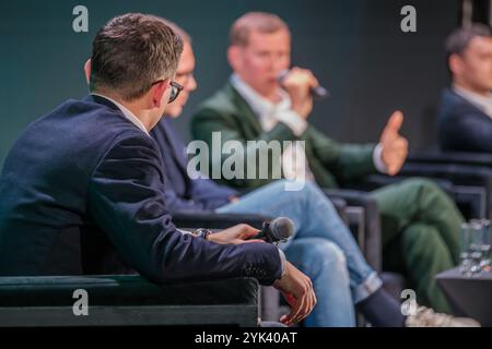 Des chefs d'entreprise engagés participent à une discussion dynamique, partageant leurs idées avec les membres du public. Des tenues professionnelles et des microphones mettent en valeur le cadre formel de l'événement. Banque D'Images