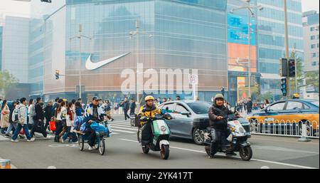 Pékin, Chine. Trafic sur la rue Wangfujing. Rue commerçante populaire à Pékin. Boutique officielle de Nike en arrière-plan. Voitures, motos qui passent Banque D'Images