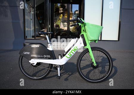 Vue latérale d'un vélo vert et blanc Lime garé sur un sentier à l'extérieur de l'entrée d'un bâtiment Banque D'Images