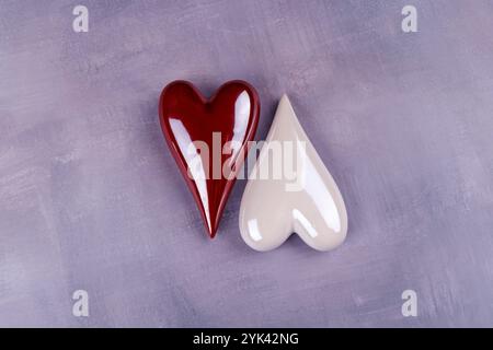 Coeurs en porcelaine rouge et blanche dispersés sur une table en ciment gris, capturant une esthétique minimaliste de la Saint-Valentin Banque D'Images