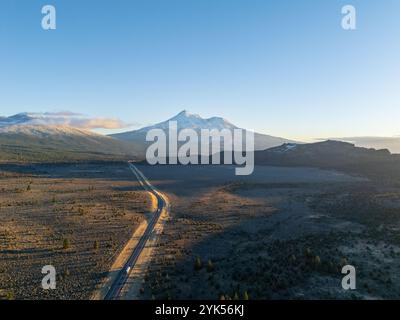 Vue aérienne du mont Shasta depuis le dessus de la route 97, Californie, au coucher du soleil, en automne, avec de la neige neuve, teintes orange, ciel clair, forêt au premier plan. Banque D'Images