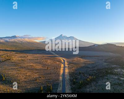 Vue aérienne du mont Shasta depuis le dessus de la route 97, Californie, au coucher du soleil, en automne, avec de la neige neuve, teintes orange, ciel clair, forêt au premier plan. Banque D'Images