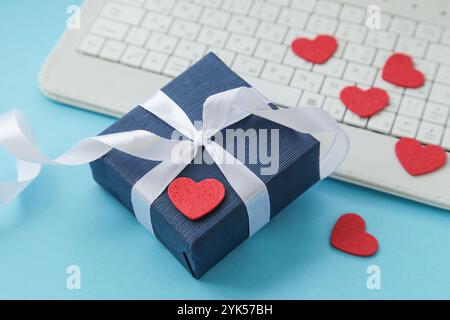 Clavier d'ordinateur, boîte-cadeau, coeurs sur fond bleu clair. Saint-Valentin. Cadeau pour hommes. Fête des pères. Cadeau pour lui. Achats en ligne. Stocker en ligne, Banque D'Images