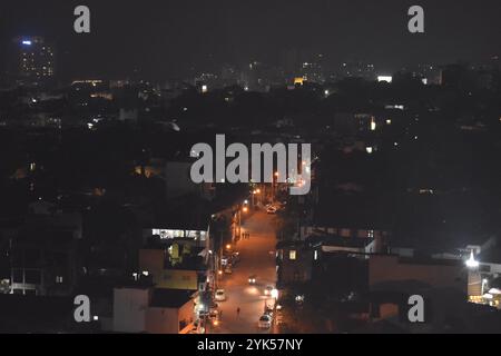 Une vue sereine de la ville la nuit, avec des lampadaires lumineux et des bâtiments lointains éclairant l'horizon urbain Banque D'Images