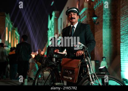 Bagdad, Irak. 13 novembre 2024. Un homme habillé en facteur se tient debout avec son vélo pendant le festival de la fête de Bagdad dans la rue Al-Saray. Bagdad Day Festival célèbre l'histoire et la civilisation de Bagdad. L'événement 'Bagdad Simulation', l'un des segments du festival qui vise à faire revivre l'atmosphère de la ville dans une période allant de 1924 à 2024 en réincarnant des personnages traditionnels et des rôles essentiels qui ont joué un rôle central dans la vie quotidienne à Bagdad. (Crédit image : © Ismael Adnan/SOPA images via ZUMA Press Wire) USAGE ÉDITORIAL SEULEMENT! Non destiné à UN USAGE commercial ! Banque D'Images