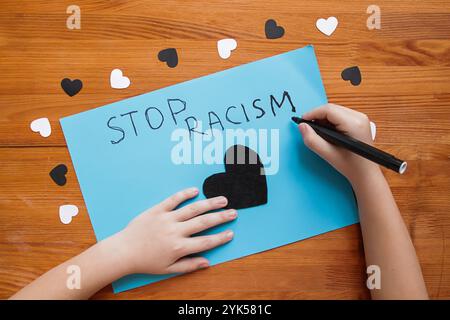 Un enfant caucasien écrit une affiche "Stop Racism". Activisme et mouvement des droits de l'homme. Arrêtez le racisme et le concept des enfants. Pas de racisme contre les enfants. Racial Banque D'Images