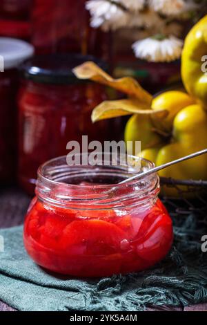 Confiture de coings dans un bocal en verre, coings dans un panier et bouquet de chrysanthèmes. Nature morte d'automne, style rustique, mise au point sélective. Banque D'Images