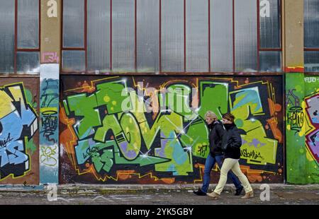 Deux personnes marchant le long d'un mur couvert de graffitis colorés, ambiance urbaine, Landau, Rhénanie-Palatinat, Allemagne, Europe Banque D'Images