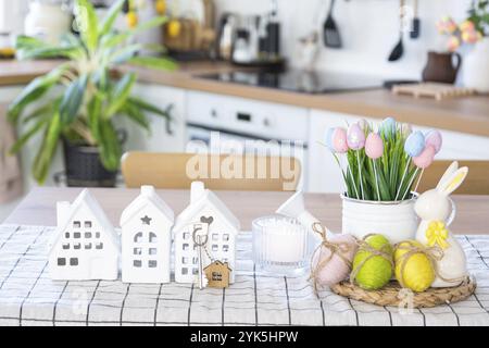 Clé de maison de maison confortable avec décor de Pâques avec lapin et œufs sur la table de la cuisine. Construction, conception, projet, déménagement à une nouvelle maison, hypothèque, assurance Banque D'Images