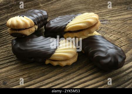 Biscuits sur la table en bois. Biscuits avec remplissage sur le bureau en bois. Biscuits sucrés trempés dans du chocolat Banque D'Images