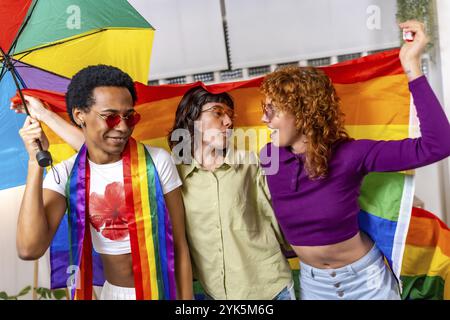 Des personnes non binaires et transgenres dansant agitant le drapeau lgbt arc-en-ciel célébrant une fête à la maison Banque D'Images