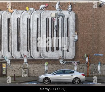 Grand graffiti mural sur le mur de briques des bâtiments de la rue Craenendonck derrière une voiture argentée garée, Louvain, région du Brabant flamand, Belgique, Europe Banque D'Images