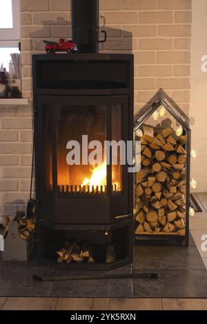 Cheminée de poêle en métal noir avec du bois dans une pile de bois, l'intérieur d'une maison de village privée. Chauffage et chauffage de la maison avec bois de chauffage, la chaleur Banque D'Images