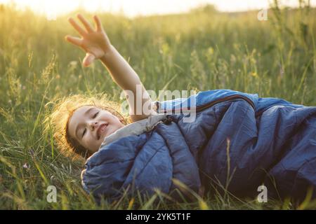 Un enfant dort dans un sac de couchage sur l'herbe dans un voyage de camping, des loisirs de plein air respectueux de l'environnement, un mode de vie sain, l'heure d'été. Doux et paisible s Banque D'Images