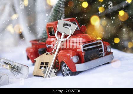 Voiture rétro rouge avec un arbre de Noël décorera avec la clé de la maison dans le pick-up pour Noël. Achat d'une maison, déménagement, hypothèque, prêt, immobilier Banque D'Images