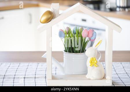 Petite maison de maison confortable avec décor de Pâques avec lapin et oeufs sur la table de la cuisine. Bâtiment, conception, projet, déménagement à la nouvelle maison, hypothèque, insuranc Banque D'Images