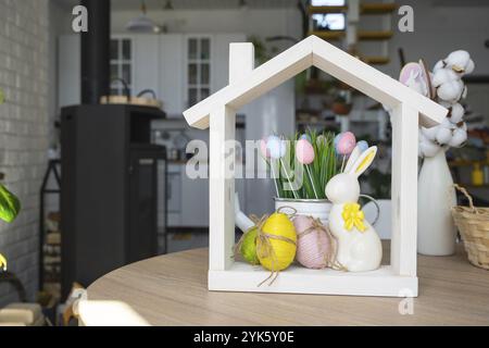 Petite maison de maison confortable avec décor de Pâques avec lapin et oeufs sur la table de la cuisine. Bâtiment, conception, projet, déménagement à la nouvelle maison, hypothèque, insuranc Banque D'Images