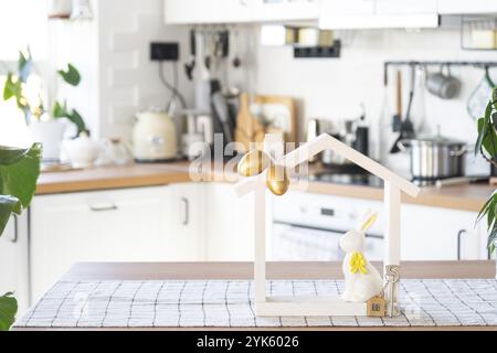 Clé et minuscule maison de maison confortable avec décor de Pâques avec lapin et oeufs sur la table de la cuisine. Bâtiment, conception, projet, déménagement à la nouvelle maison, hypothèque, Banque D'Images