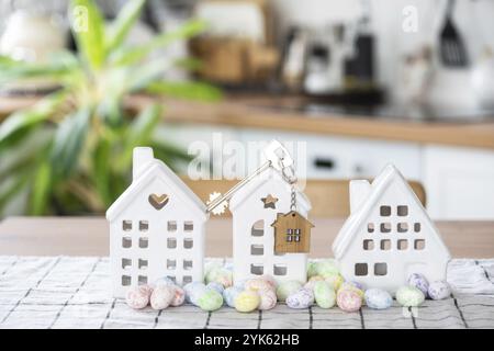 Clé de maison de maison confortable avec décor de Pâques avec lapin et œufs sur la table de la cuisine. Construction, conception, projet, déménagement à une nouvelle maison, hypothèque, assurance Banque D'Images
