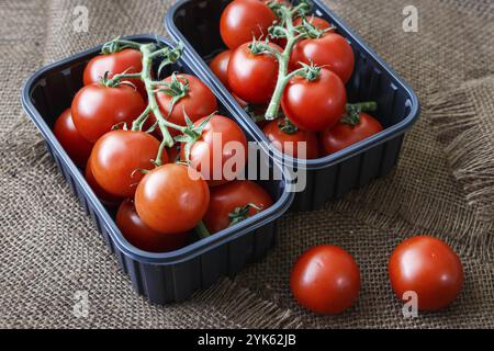 Tomates cerises dans un contenant en plastique sur fond brun Banque D'Images