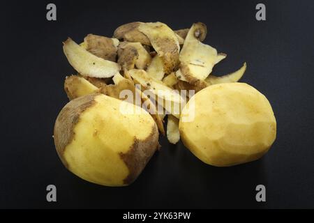 Pommes de terre pelées brut et de pommes de terre entières sur fond noir Banque D'Images