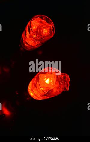 Des glaçons rouges brillants flottent dans des verres à champagne avec une boisson. Les objets en plastique fabriqués sous forme de glaçons avec une diode intégrée s'illuminent. Banque D'Images