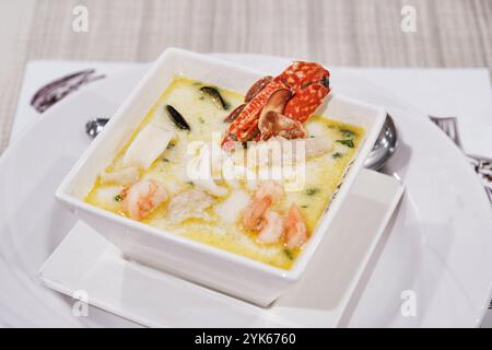 Soupe crémeuse de fruits de mer. Crabe, crevettes, calmars, moules et herbes dans un bouillon avec du lait de coco. Banque D'Images