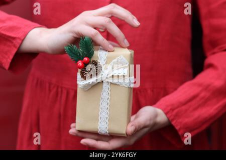 Femme en robe rouge tenant la boîte cadeau de Noël, vue rapprochée. Concept de célébration de Noël. Banque D'Images