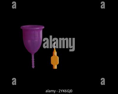 Coupe menstruelle avec une brosse de nettoyage spéciale isolée sur fond noir avec espace de copie. Banque D'Images