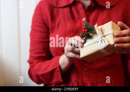 Femme en robe rouge tenant la boîte cadeau de Noël, vue rapprochée. Concept de célébration de Noël. Banque D'Images