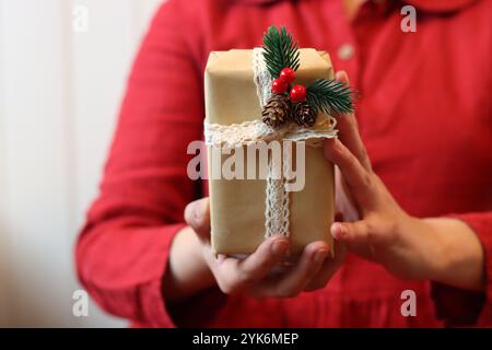 Femme en robe rouge tenant la boîte cadeau de Noël, vue rapprochée. Concept de célébration de Noël. Banque D'Images