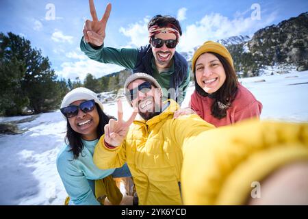 Selfie de l'homme caucasien et femme latina regardant souriant à la caméra sur la montagne de neige en vacances. Banque D'Images