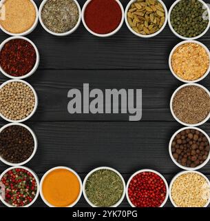 Cadre d'épices assorties dans des bols en céramique blanche sur fond de table en bois sombre avec espace de copie, vue de dessus surélevée, directement au-dessus Banque D'Images