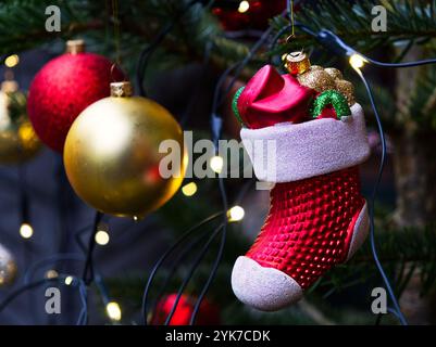 Sapin de Noël suspendu chaussette rouge Père Noël, ornements et lumières photo en gros plan de haute qualité Banque D'Images