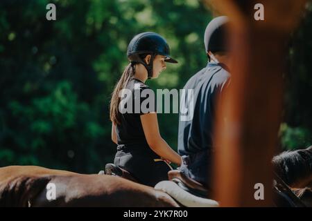 Deux jeunes équestres à cheval dans une forêt verdoyante Banque D'Images