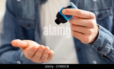 Jeune homme qui verse du gel désinfectant sur les mains pour la désinfection Banque D'Images