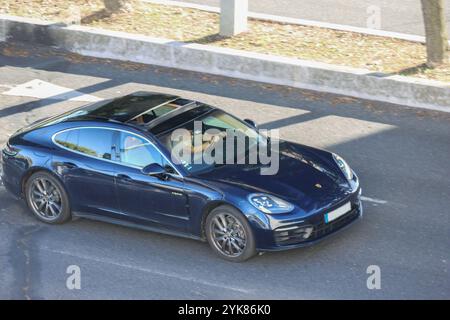 Homme d'affaires conduit une porsche panamera bleue moderne sur une route pendant une journée d'été Banque D'Images