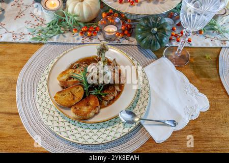 Ragoût de soupe de canard rôti avec pain à l'ail sur bol et assiette en porcelaine fine et cuillère en argent pour un dîner de Thanksgiving. Banque D'Images