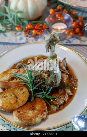 Ragoût de soupe de canard rôti avec pain à l'ail sur bol et assiette en porcelaine fine et cuillère en argent pour un dîner de Thanksgiving. Banque D'Images