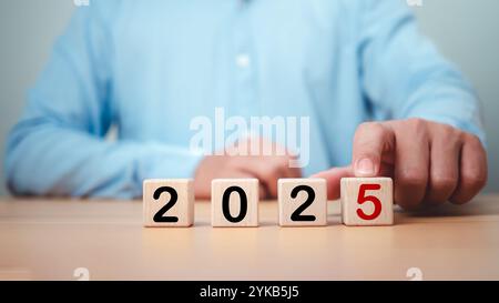 Homme d'affaires sélectionné cube de 2025 sur la table en bois, planification 2025 tendances symbole de nouvelle année, mots conceptuels 2025 commencent sur de beaux blocs de bois, Busine Banque D'Images