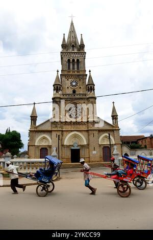 Un Pous Pous conducteur par la cathédrale dans le centre d'Antsirabe à Madagascar. Banque D'Images