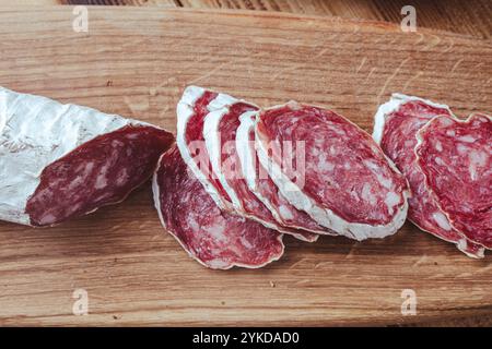 Tranches de fuet de salami traditionnel espagnol ou de saucisse sèche, recouvertes de moisissure fermentée sur une table en bois. Photo de haute qualité Banque D'Images