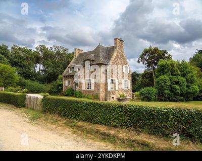 Plevenon, France - 20 juillet 2024 : charmante maison traditionnelle bretonne en pierre avec un toit en pente, entourée de verdure et d'une haie bien entretenue. Banque D'Images