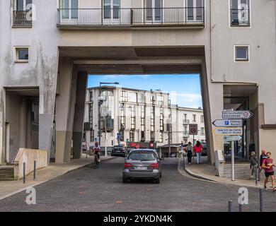 Brest, France - 24 juillet 2024 : Une scène urbaine moderne à Brest avec une rue passant par une grande arche architecturale. Voitures et cyclistes naviga Banque D'Images