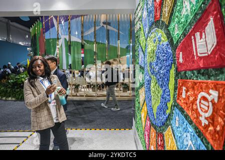 Bakou, Azerbaïdjan, Azerbaïdjan. 16 novembre 2024. Une femme se tient debout devant un panneau d’affichage SDG fait de bouchons de bouteilles en plastique et en forme de logo SDG dans la section Pavillon du site de la COP29 tenue au stade olympique de Bakou. Les objectifs de développement durable (ODD) font partie intégrante du maintien de la cohésion entre les pays membres, comprenant 17 objectifs ciblés affectés par les défis mondiaux actuels, de l’environnement à la pauvreté, des droits de l’homme à l’économie et plus encore. Depuis le COVID, il y a eu un «rattrapage» sur le temps perdu et une lutte contre la division croissante dans le monde entier. (Crédit image : © Bian Banque D'Images