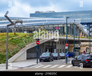 Rennes, France - 26 juillet 2024 : entrée de la gare moderne avec façade en verre et sculpture en métal, avec voitures garées et panneaux de signalisation dans le fo Banque D'Images