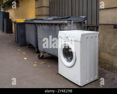 Une machine à laver jetée placée à côté de poubelles couvertes de graffitis dans une rue de la ville de Rennes en Bretagne Banque D'Images